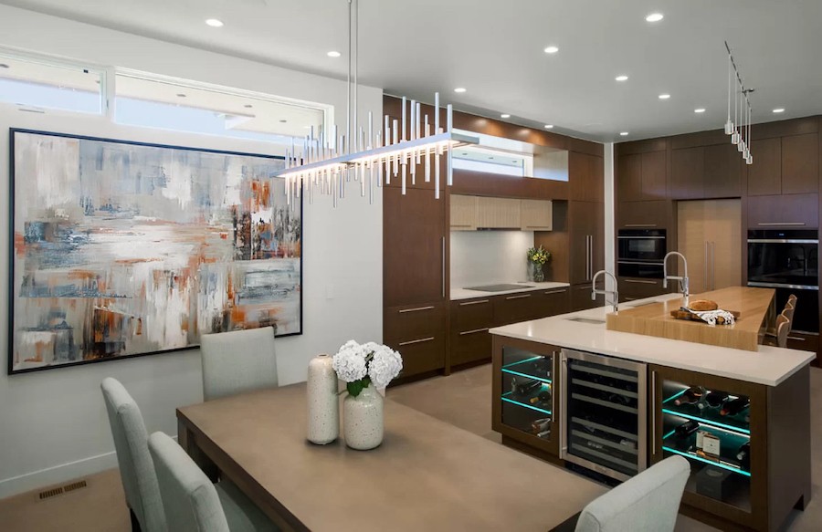 Dining table in foreground with the kitchen area and large abstract artwork in the background.