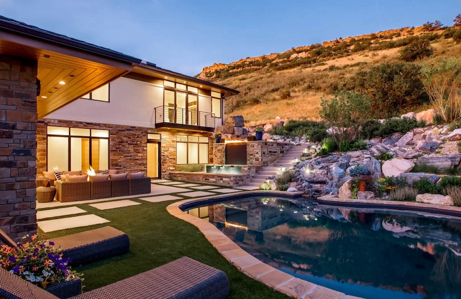 Backyard view featuring pool, two-story home, seating area and Colorado mountains in the background 