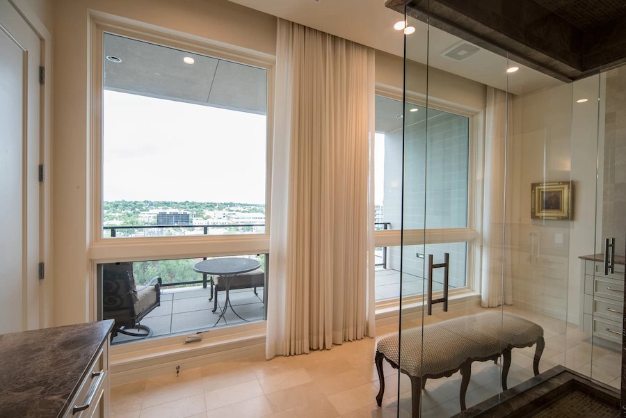 bathroom area overlooking balcony through large floor-to-ceiling windows with motorized shades