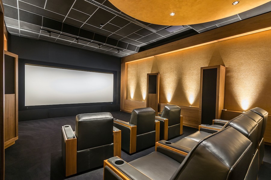 Luxury home theater with dark leather seating and a large movie screen.