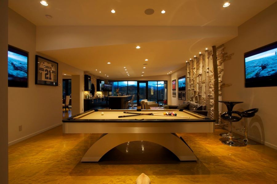 A media room with a pool table, multiple TV displays, and a bar area.