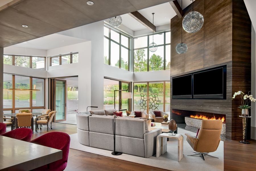 A great room with two displays, a lit fireplace, and multiple pendant lights.